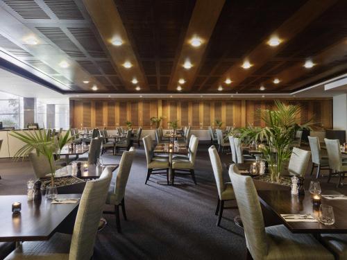 a restaurant with tables and chairs in a room at ibis Auckland Ellerslie in Auckland