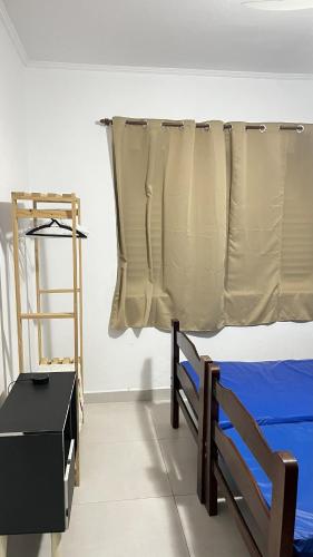 a bedroom with a bed with a curtain and a shelf at Mongaguá Apartamento in Mongaguá