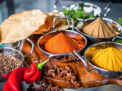 a wooden cutting board with different types of spices at Novotel Auckland Ellerslie in Auckland