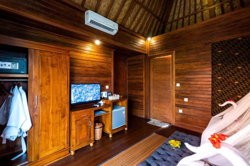 a room with wood paneled walls and a television at Golo Pada Villa Labuan Bajo by ABM in Nggorang