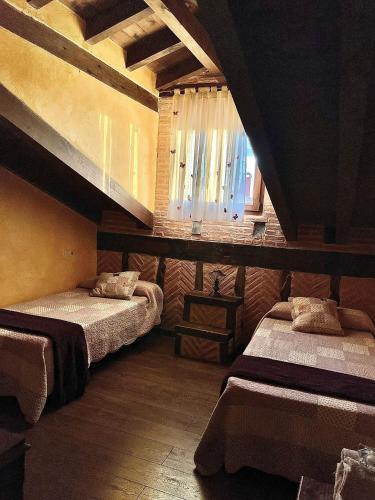a room with two beds and a window in it at Casa Rural La Charolesa in Aguilera