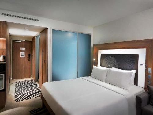 a bedroom with a large white bed and a chair at Novotel London Tower Bridge in London