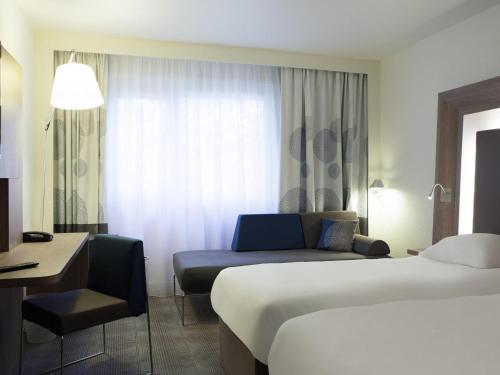 a hotel room with two beds and a couch at Novotel London Tower Bridge in London
