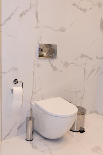a white toilet in a bathroom with marble walls at Pava De Luxe in Berehove