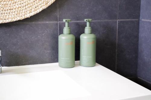 two green bottles sitting on a counter in a bathroom at Spacious Family Retreat on the edge of Tenterfield in Tenterfield