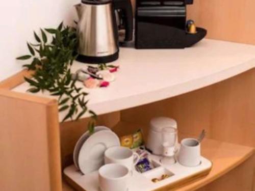 a shelf with cups and plates and a coffee maker at Ibis Poznan Stare Miasto in Poznań