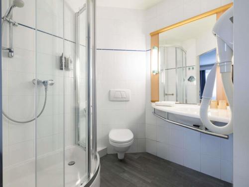 a bathroom with a shower and a toilet and a sink at Ibis Poznan Stare Miasto in Poznań