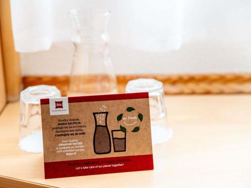 a sign on a table with two wine glasses at Ibis Poznan Stare Miasto in Poznań