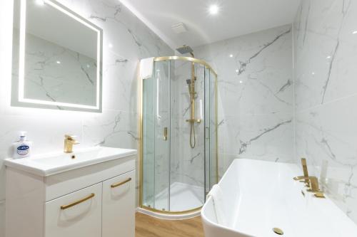 Un baño blanco con ducha y lavabo. en Where Style Meets Comfort The New Forest Home, en Southampton