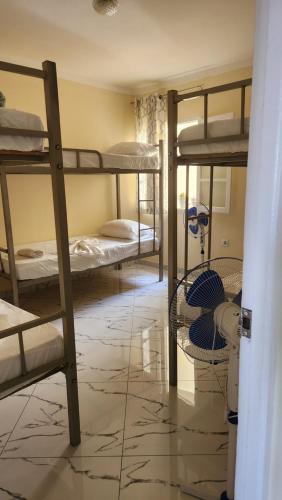a room with three bunk beds in a room with a tile floor at FREE Early Check In-RESERVATIONS ONLY-No Walk-Ins- & CARD PAYMENTS-No Cash-Meeting Point Volcanic Beach Refuge in São Filipe
