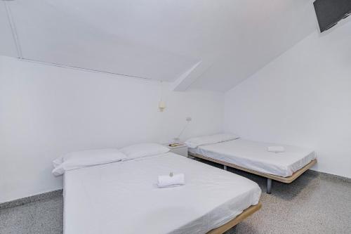 two beds in a room with white walls at Casa de las Nieves in Granada