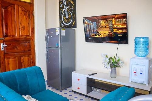 Una sala de estar con una silla azul y un refrigerador. en Little escalade, en Mombasa