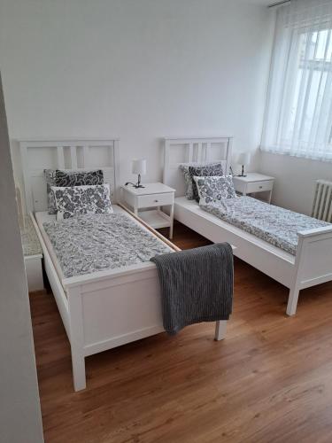 two beds in a white room with two tables at Apartmans MWM Brno 3 in Brno