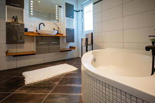 a bathroom with a tub and a sink at EHM Elegantes Design Apartment zwischen Linz&Wels in Pucking