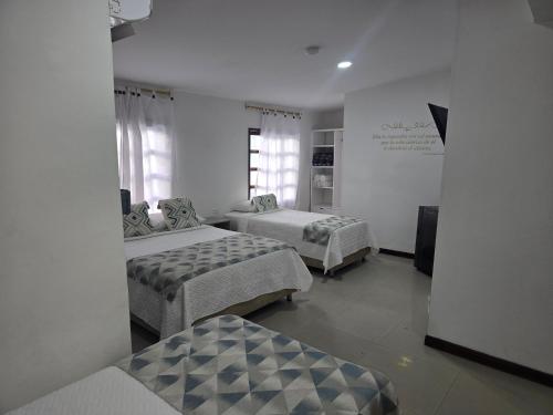 a bedroom with two beds and a wall with windows at Hotel Rodadero Dorado in Santa Marta