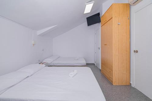 a small room with two beds and a wooden cabinet at Casa de las Nieves in Granada