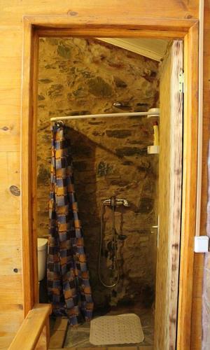 a bathroom with a shower in a stone wall at Casa do Moinho Novo in Fontão Fundeiro