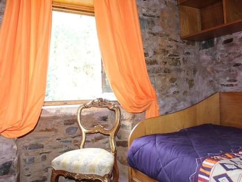 a bedroom with a bed and a chair and a window at Casa do Moinho Novo in Fontão Fundeiro