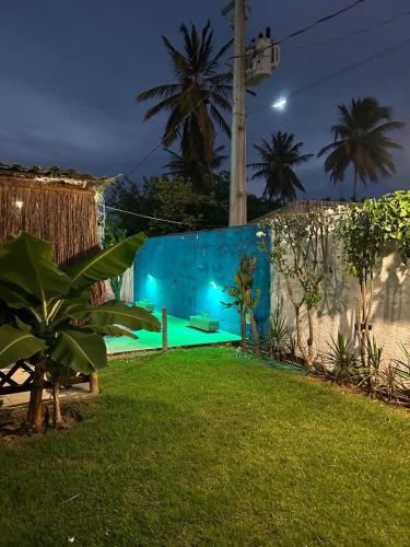 a backyard at night with a blue wall at Chalés XIÉ in São Miguel dos Milagres