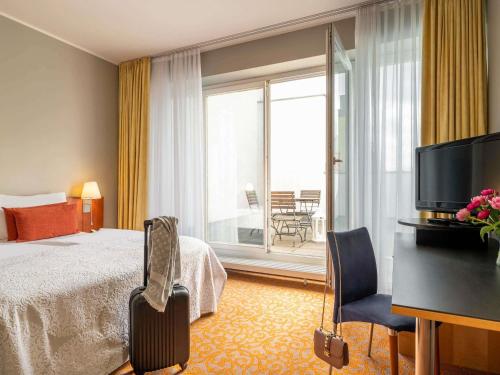 a hotel room with a bed and a balcony at Mercure Hotel & Residenz Berlin Checkpoint Charlie in Berlin