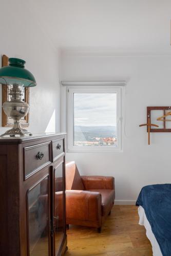 a bedroom with a chair and a window at Memórias Charme Residences in Covilhã