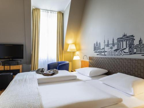 a hotel room with two beds and a tv at Mercure Hotel & Residenz Berlin Checkpoint Charlie in Berlin