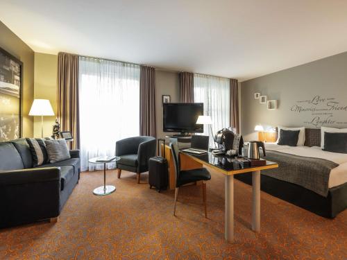 a hotel room with a bed and a desk at Mercure Hotel & Residenz Berlin Checkpoint Charlie in Berlin