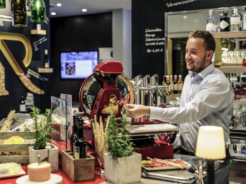 a man standing behind the counter of a bar at Mercure Hotel & Residenz Berlin Checkpoint Charlie in Berlin