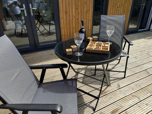 a black table with a bottle of wine and two glasses at Driftwood at BotanyBay - Dogs Welcome in Broadstairs