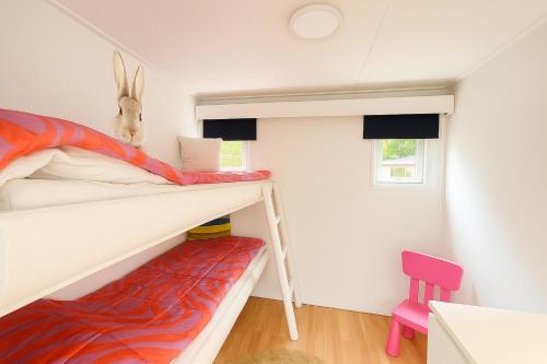 a small bedroom with a bunk bed and a chair at Gezellig chalet met 2 slaapkamers en zicht op het water in Erm
