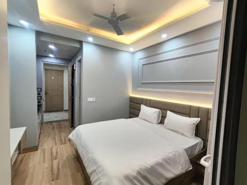 a bedroom with a white bed with a ceiling fan at Anmolairbnb in Greater Noida