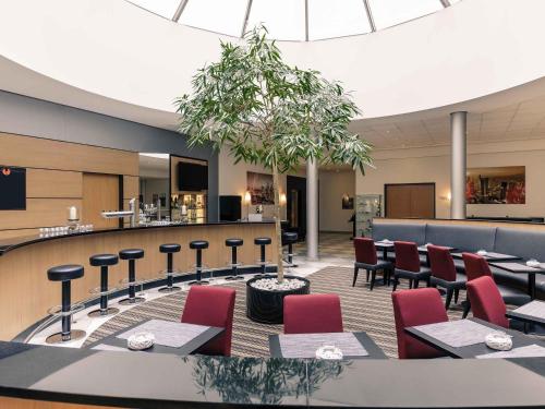 a waiting room with tables and chairs and a bar at Mercure Hotel Frankfurt Eschborn Süd in Eschborn
