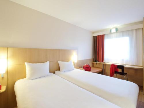 a bedroom with a large white bed with a window at Ibis Warszawa Ostrobramska in Warsaw