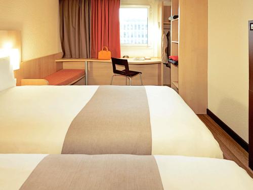a hotel room with a large bed and a chair at Ibis Warszawa Ostrobramska in Warsaw