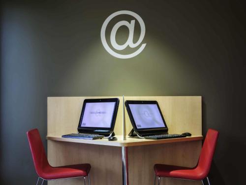two laptops sitting on a counter with red chairs at Ibis Cornella in Cornellà de Llobregat