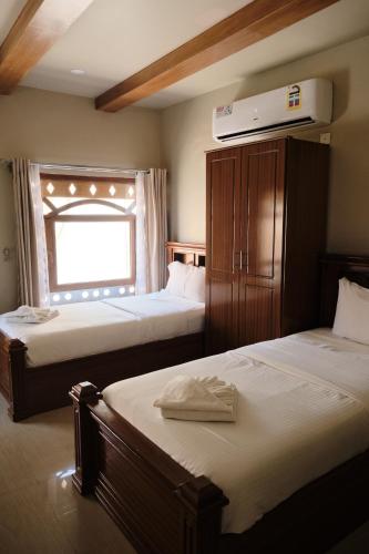 a hotel room with two beds and a window at Durrat Nizwa Inn in Nizwa