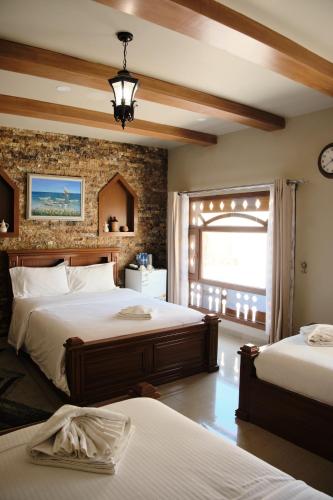 a bedroom with two beds and a brick wall at Durrat Nizwa Inn in Nizwa