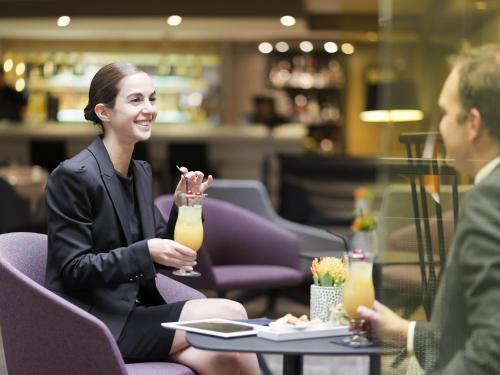 a woman sitting at a table with a drink at Novotel Genève Centre in Geneva