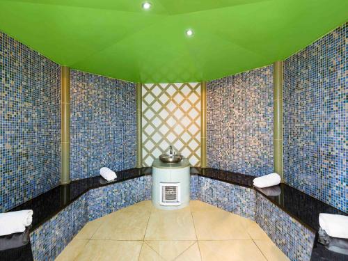 a bathroom with blue tiles and a green ceiling at Novotel Genève Centre in Geneva