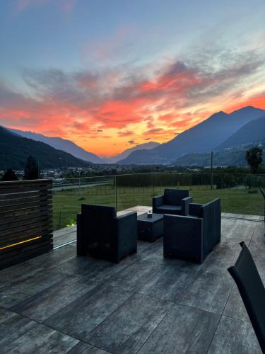 a sunset with couches on a patio with mountains at B&B Valtellina Mon Amour in Piateda