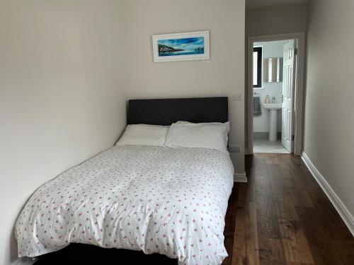 ein weißes Schlafzimmer mit einem Bett und einem Badezimmer in der Unterkunft Sunberry 2 Bright Modern Entire Home, Headford in Headford