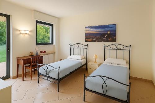 two beds in a room with a table and a desk at L'angolo verde apartment in Moncalieri