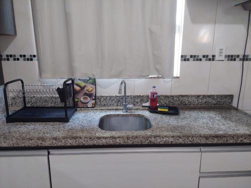 a kitchen counter with a sink and a window at Home furnished in condominium in Macapá