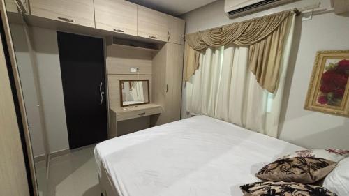 a bedroom with a white bed and a window at Home furnished in condominium in Macapá