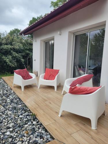 eine Terrasse mit drei weißen Stühlen und roten Kissen in der Unterkunft chambre spacieuse et calme in Ahetze