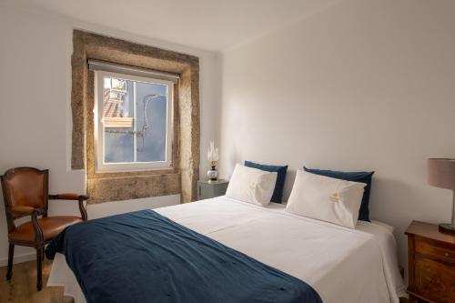 a bedroom with a white bed and a window at Memórias Charme Residences in Covilhã