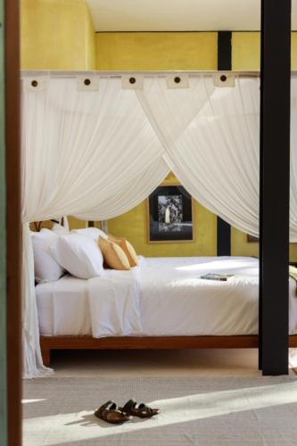 a bedroom with a canopy bed with a pair of shoes at Sumba Lodge in Manuel Antonio