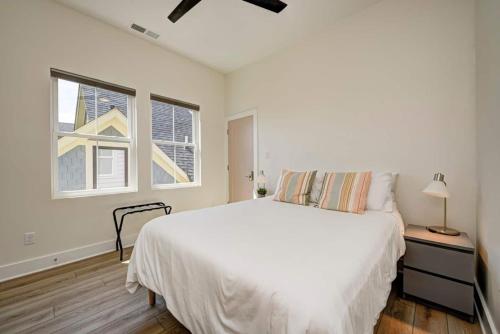 a white bedroom with a bed and a window at It's All Good - Two Homes Sleeps 18 in Indianapolis