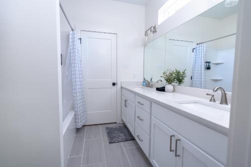 a white bathroom with a sink and a mirror at The Blue Heron Haven in Baton Rouge