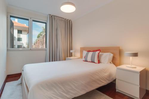 una camera da letto con un letto bianco e una finestra di Funchal City Nest a Funchal